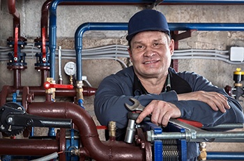 Smiling custodian holding a wrench.